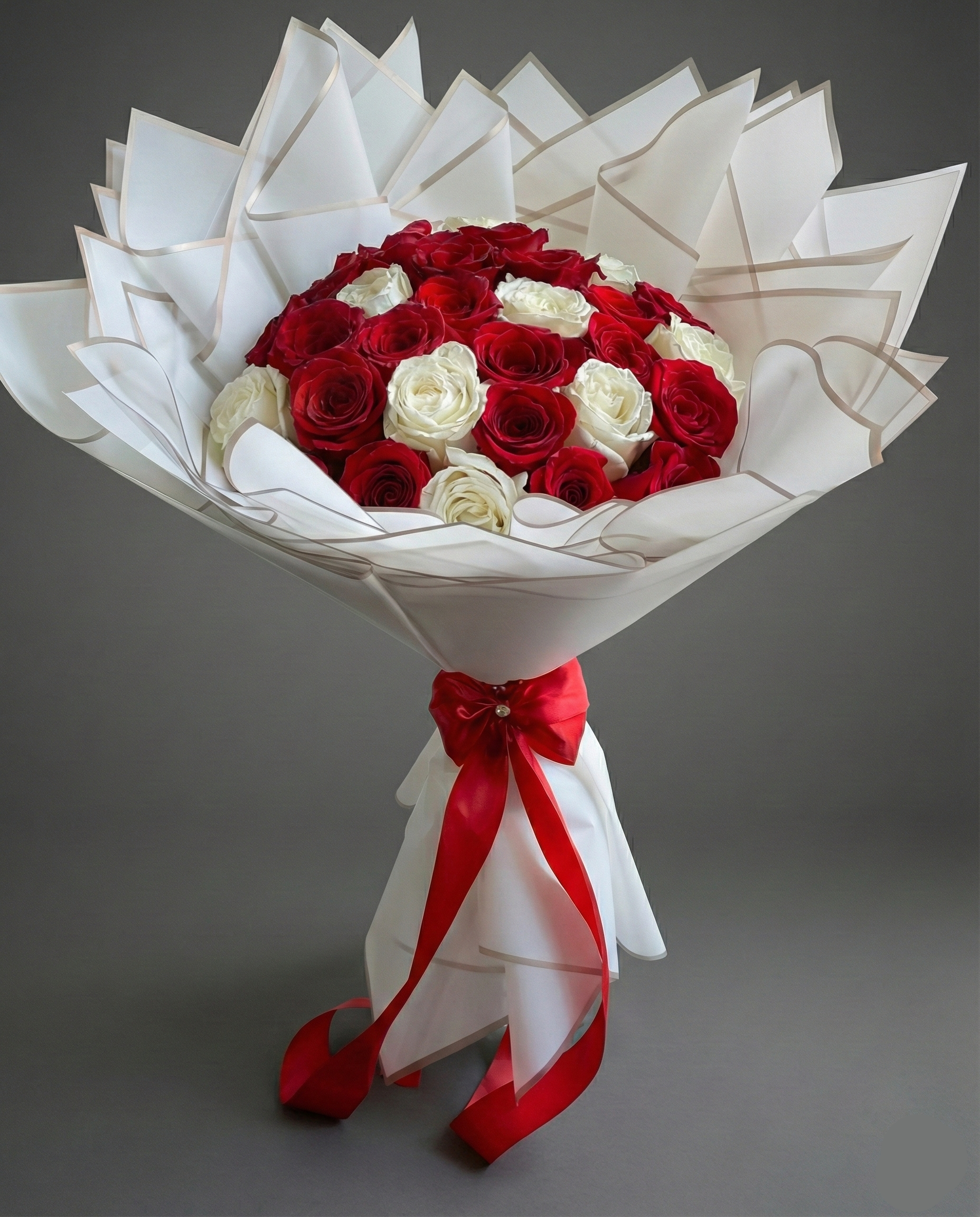 Bouquet of red and white roses with a red ribbon on a gray background