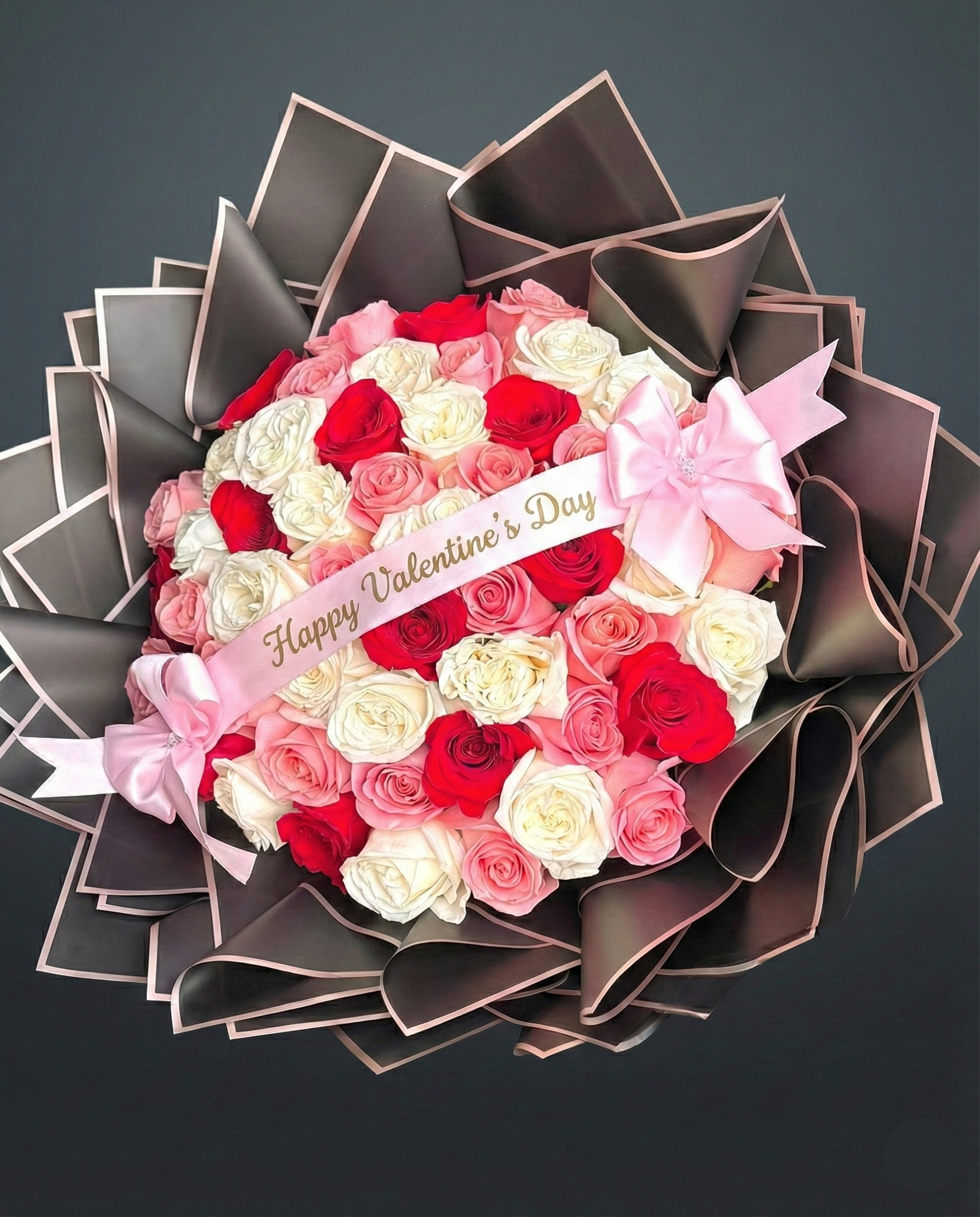 Valentine's Day bouquet with red, white, and pink roses on a dark background
