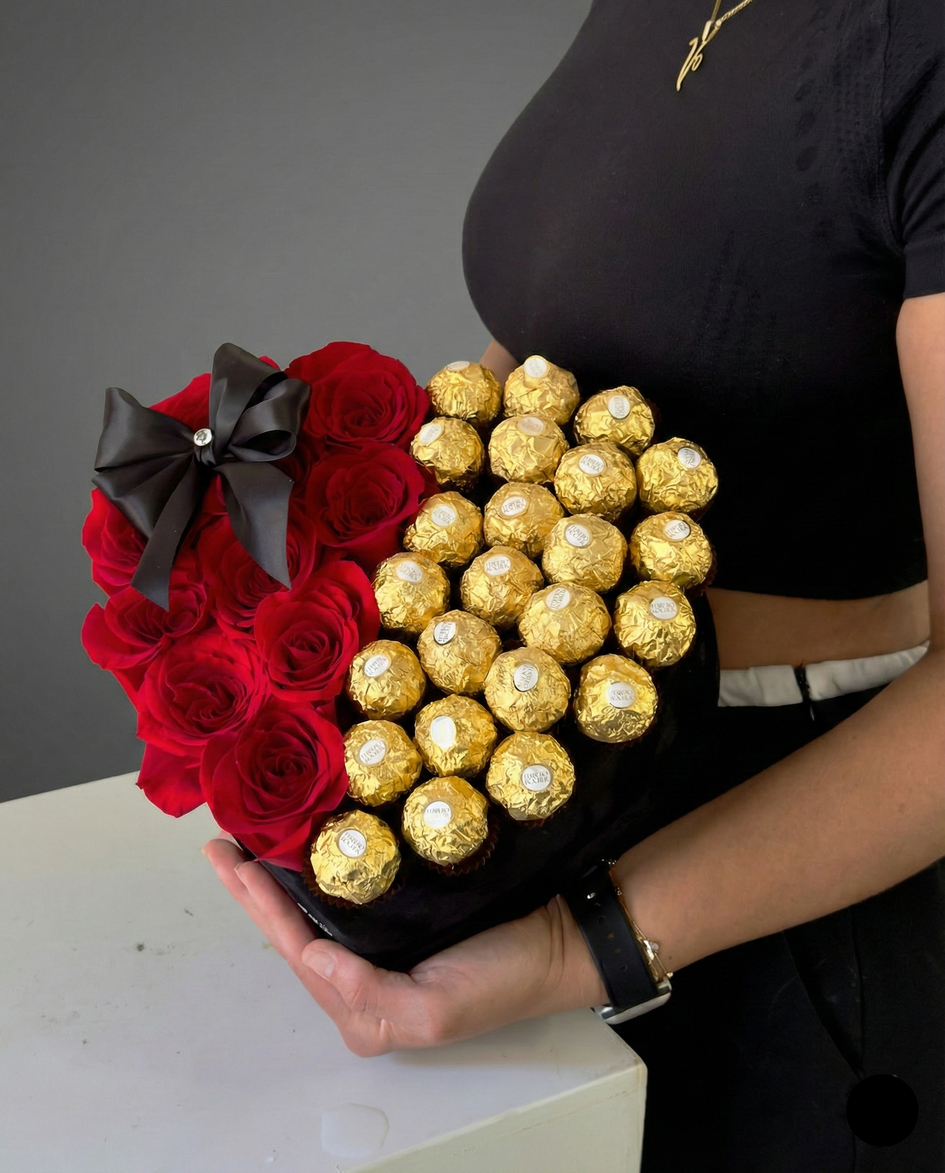 Bouquet of red roses and gold Ferrero Rocher chocolates held by a person.